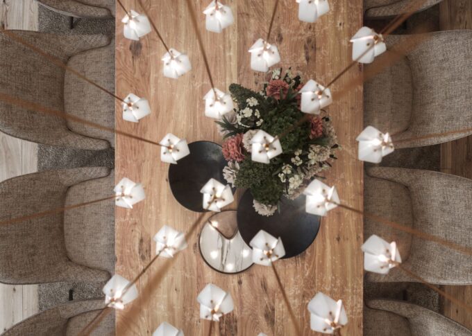 Interior 3D rendering of the Infinity light-colored wooden dining table, with many lamps on it and chairs with a similar shade